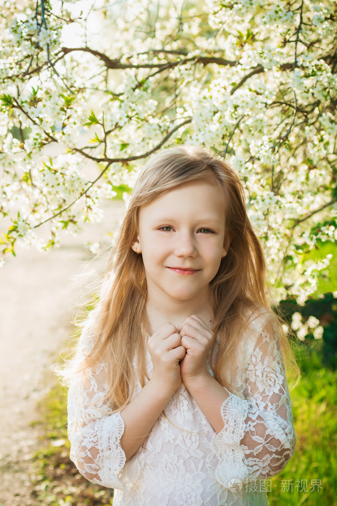 在一个阳光明媚的春天花园穿白裙子的小女孩