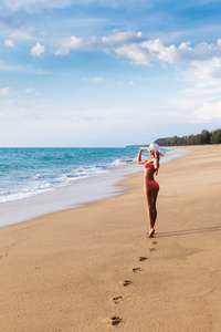 那个年轻的女人在比基尼在沙滩上的一顶帽子