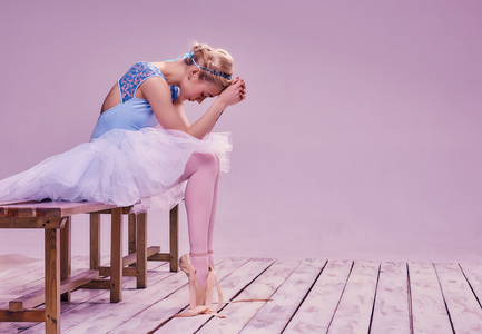 累了的芭蕾舞演员坐在木地板上
