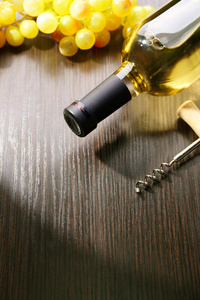 瓶装酒的葡萄和开瓶器木背景