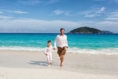 快乐的父亲和儿子在一起运行在海滩