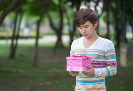 男性抱着一个粉红色的礼物盒