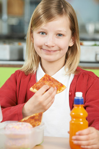 女孩坐在学校食堂吃不健康投入餐桌