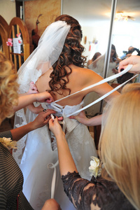 伴娘帮助搭售弓上的婚纱的新娘