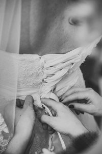 伴娘帮助搭售弓上的婚纱的新娘