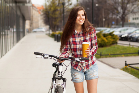 年轻漂亮的女人，与杯咖啡和一辆自行车
