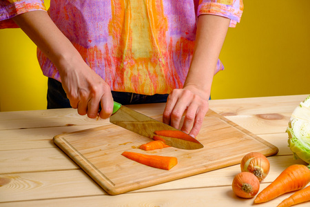 女人切胡萝卜木板和她周围的蔬菜