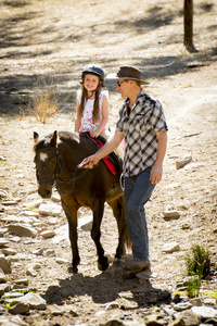 年轻的马孩子骑小马户外满意作为马教练在牛仔看父亲角色