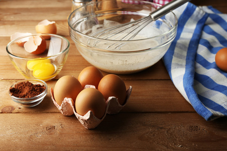 把鸡蛋放在木制的背景上的玻璃碗奶油的制备