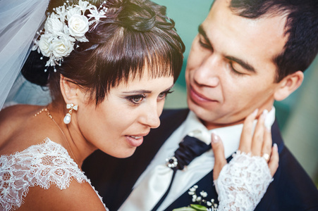 接吻的结婚礼服的年轻夫妇。新娘控股束鲜花