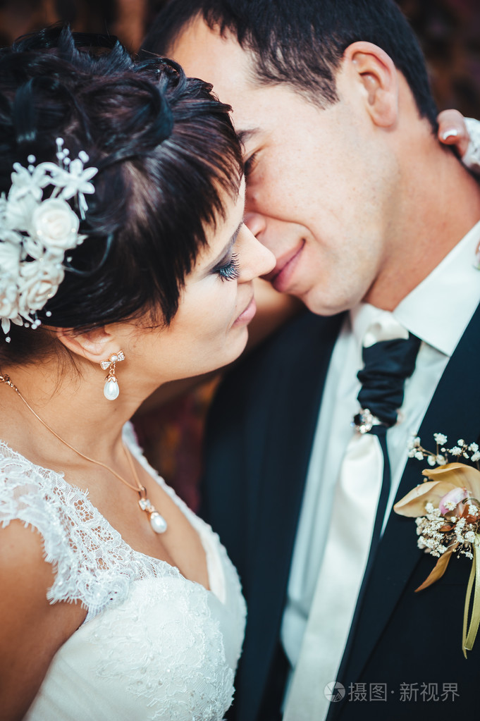 接吻的结婚礼服的年轻夫妇.新娘控股束鲜花