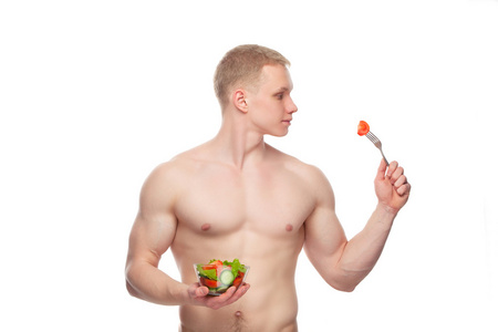 吃一份沙拉，在白色背景的年轻快乐的肌肉男