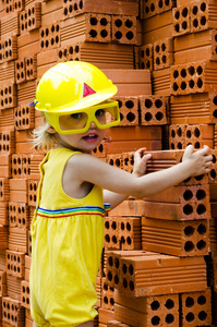 微笑与安全帽在橙色砖背景的孩子