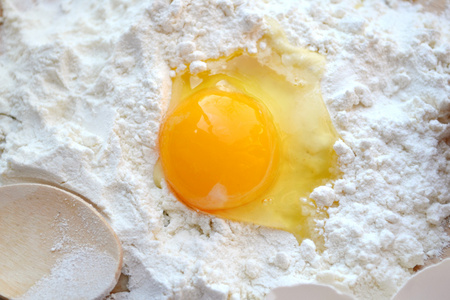 白面粉用鸡蛋 黄油和木勺烹饪板上