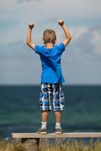 紧握拳头的男孩一个小男孩举着手指手背压碎白纸,将其举到白色背景上