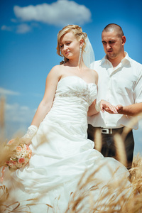 年轻美丽的婚礼夫妇在草地场中拥抱耳