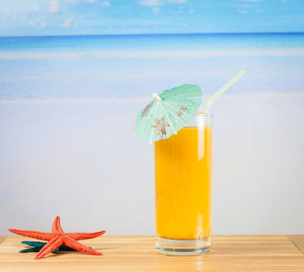 杯橙汁附近海星的海和桑迪海滩上