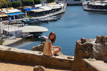 坐在海岸在希腊克里特岛上的女人