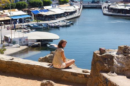 坐在海岸在希腊克里特岛上的女人