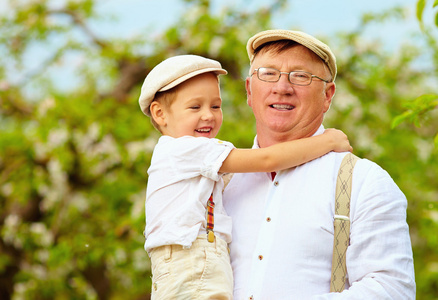 可爱的爷爷和孙子一起在春天的花园里的手上