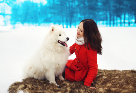 幸福的女人所有者拥有白色萨摩耶犬在户外的乐趣