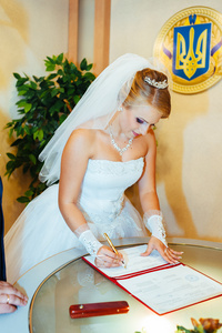 婚礼仪式。书记官处办公室。这对新婚夫妇签署婚姻文档。年轻夫妇签署文件的婚礼