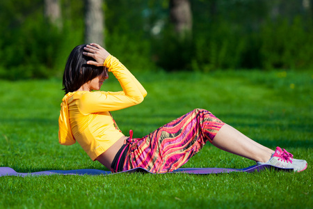 锻炼健身的女人坐在外的期间运动量来找到 ups 运动训练。快乐健康的女孩做侧仰卧起坐与高架腿同时微笑快乐