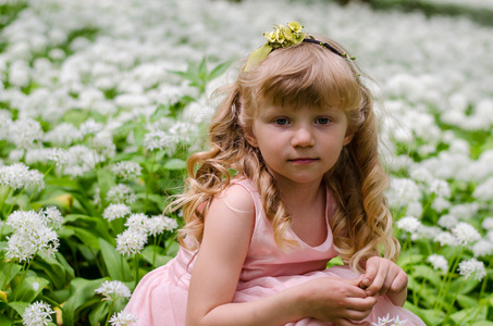 美丽的金发女孩坐在白色的草地