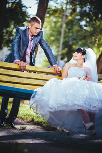 新娘和新郎在婚礼当天到户外散步在春天性质。新婚夫妇，祝新婚快乐女人和男人拥抱绿色的公园里。爱婚礼情侣户外