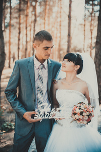 新娘和新郎在婚礼当天到户外散步在春天性质。新婚夫妇，祝新婚快乐女人和男人拥抱绿色的公园里。爱婚礼情侣户外