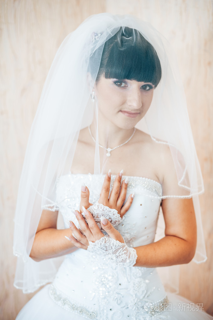 美丽的新娘准备在白色的婚纱礼服发型与亮妆快乐的性感女孩等待新郎