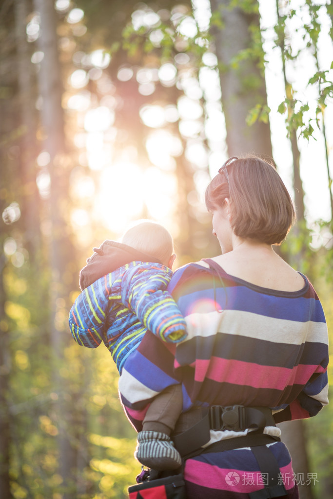 年轻的母亲背着她的宝贝儿子散步
