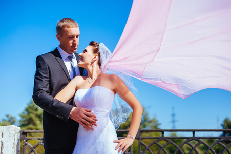 新婚的 couple.wind 起重长长的白色婚纱。新娘与新郎同粉红色披肩