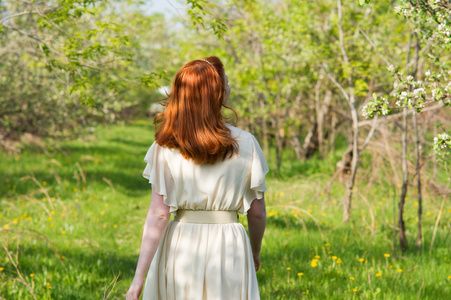 漂亮的红发女孩走在苹果园