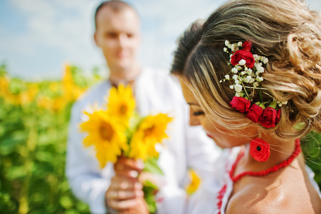 美丽的夫妇身穿传统服装在向日葵的婚礼