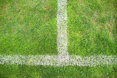 在自然足球草地上画白线的十字架。人造的绿色草坪纹理