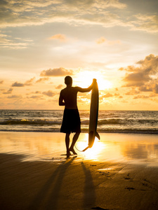 巴厘岛日落时的海滩上的冲浪者