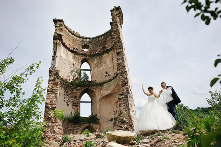 美丽的新婚夫妇在废墟附近旧塔城堡