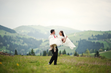 新婚夫妇在喀尔巴阡山脉。新郎持有的新娘