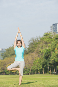 亚洲女人让瑜伽在公园叫树式