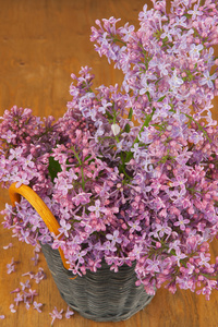 在木制的桌子上篮子里的紫丁香鲜花