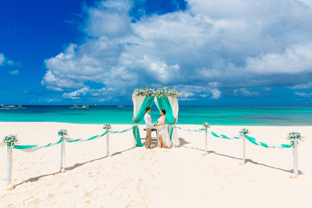 婚礼仪式在蓝色的热带海滩上。幸福的新郎和 br