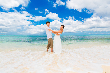 幸福的新郎和新娘在热带沙滩上玩耍。我们