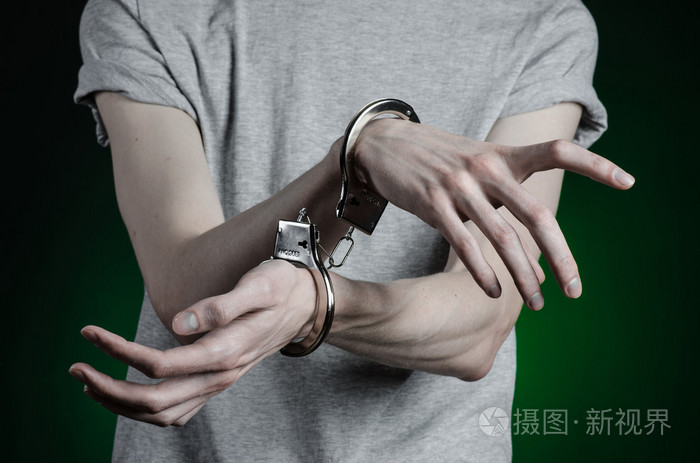 监狱和被定罪的主题: 人与灰色的 t 恤在他手上的手铐和蓝色牛仔裤的