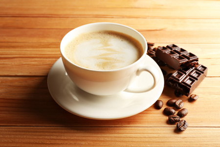 Cup 的咖啡拿铁艺术与粮食和巧克力对木制背景