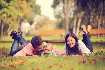 坐在公园的草地上的小女孩的父母