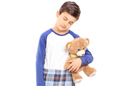 昏昏欲睡的男孩抱着一只泰迪熊