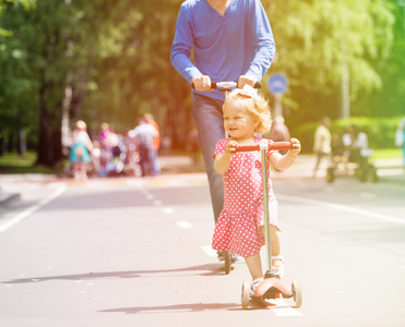 快乐的小女孩，爸爸在滑板车在城市