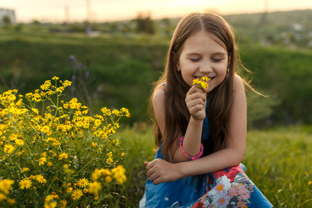 嗅到一朵黄色的花的小女孩
