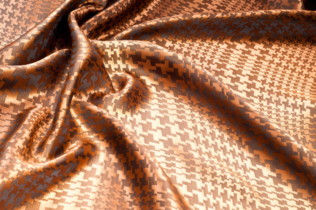 丝绸织物的质地涂上棕色图案。 棕色条纹织物工作室的宏观纹理。 艺术织物纹理折叠波浪。